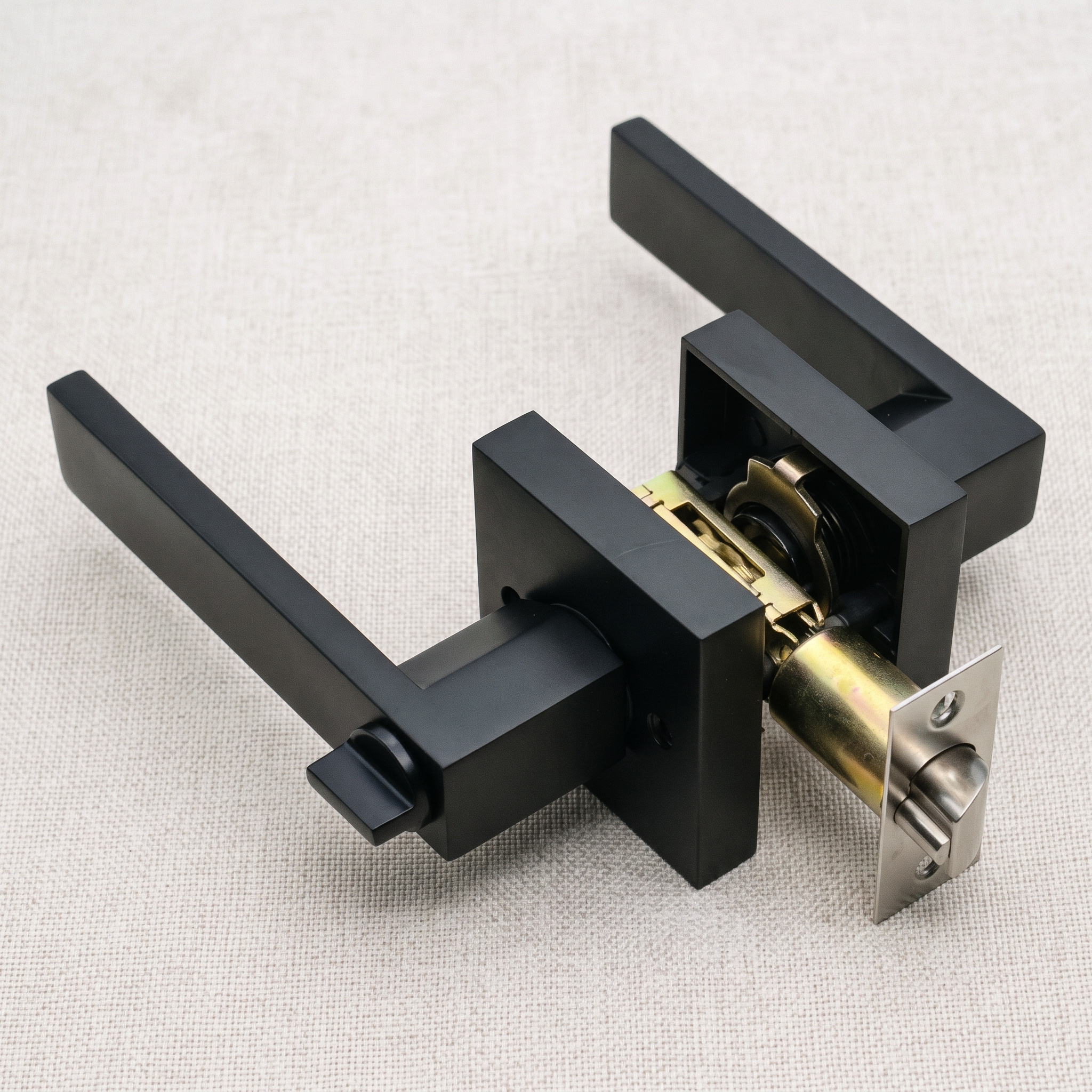 Angled view of a matt black square-rose keyed door handle lock with its latch, on a pale linen surface