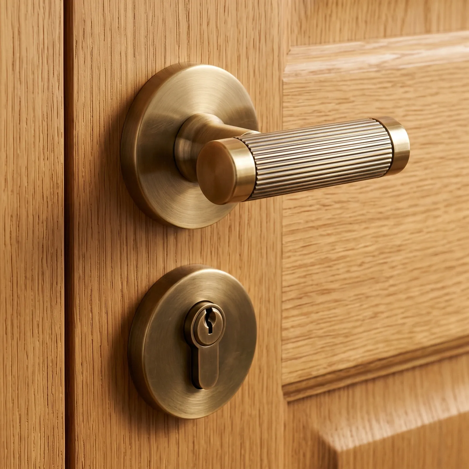 Gold fluted brass lever door handle on its round rose fitted to an oak interior door leaf.