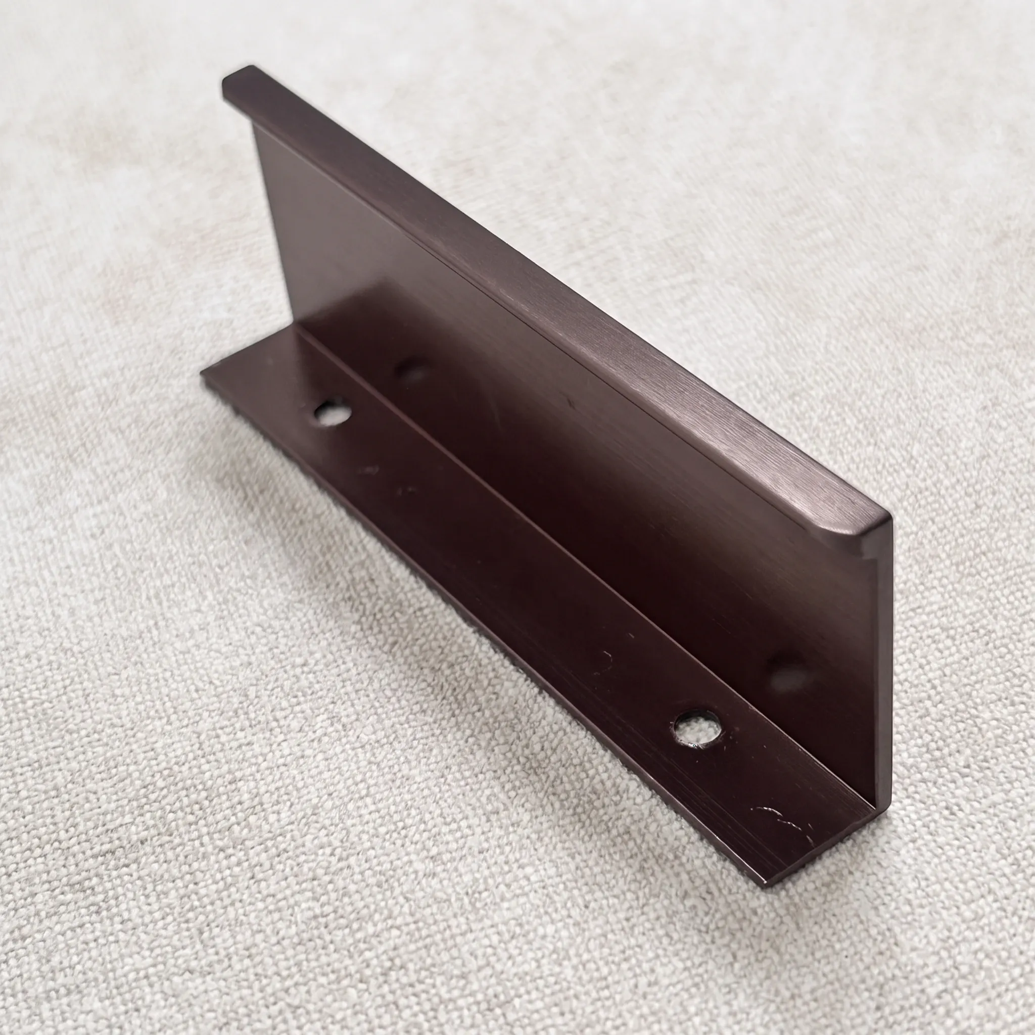 Rear of the side-mounted edge pull resting on linen, showing the flange and its countersunk mounting holes