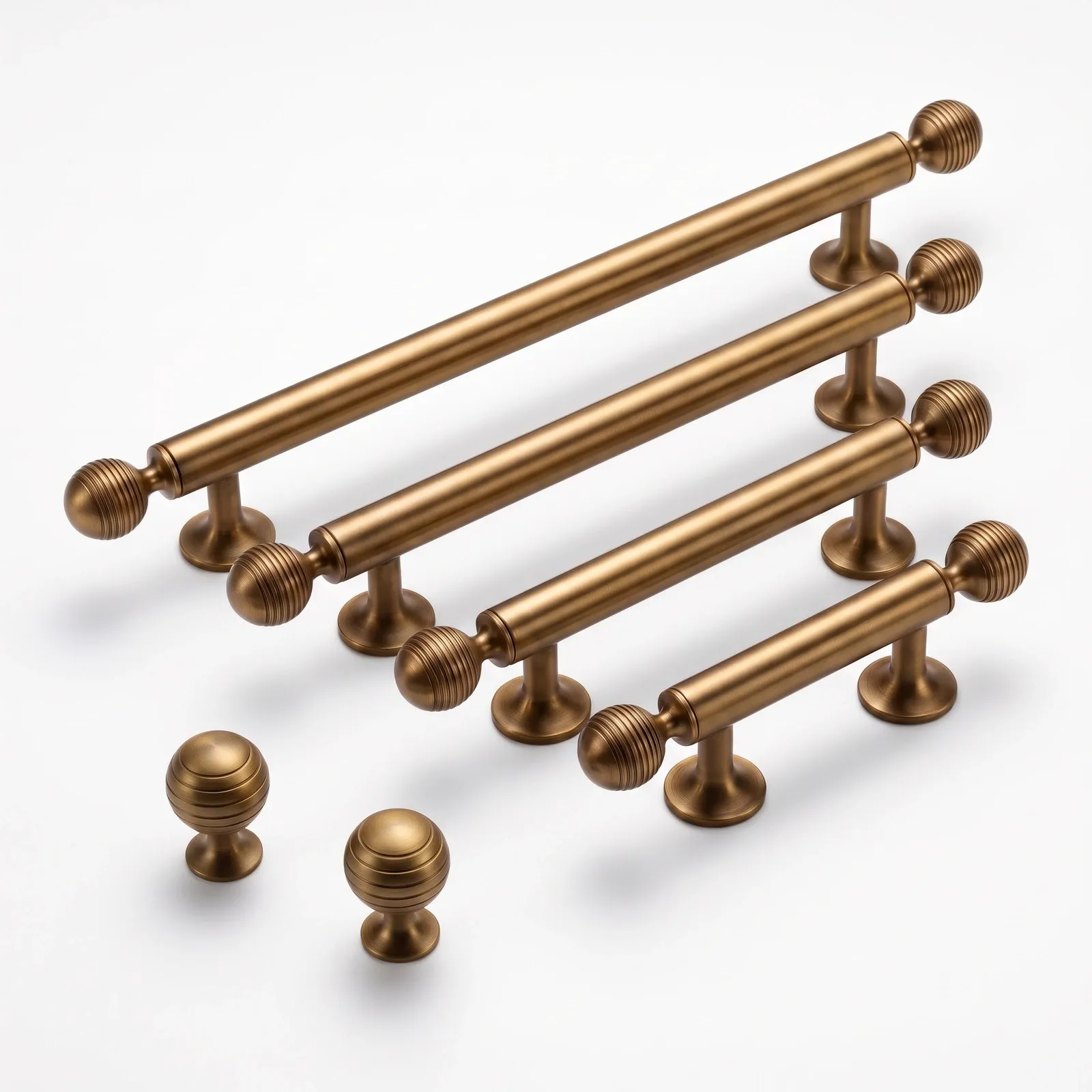 Brass Gold bar pulls in graduated lengths with grooved ball ends and banded round knobs on a white background.