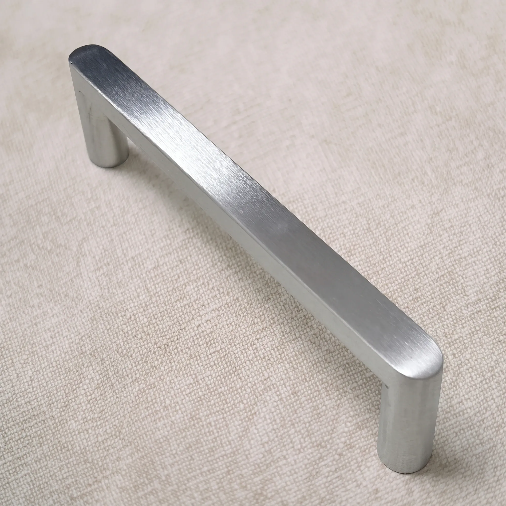 Raised three-quarter view of the flat-sided stainless pull on linen, showing the broad flat band and both cylindrical legs
