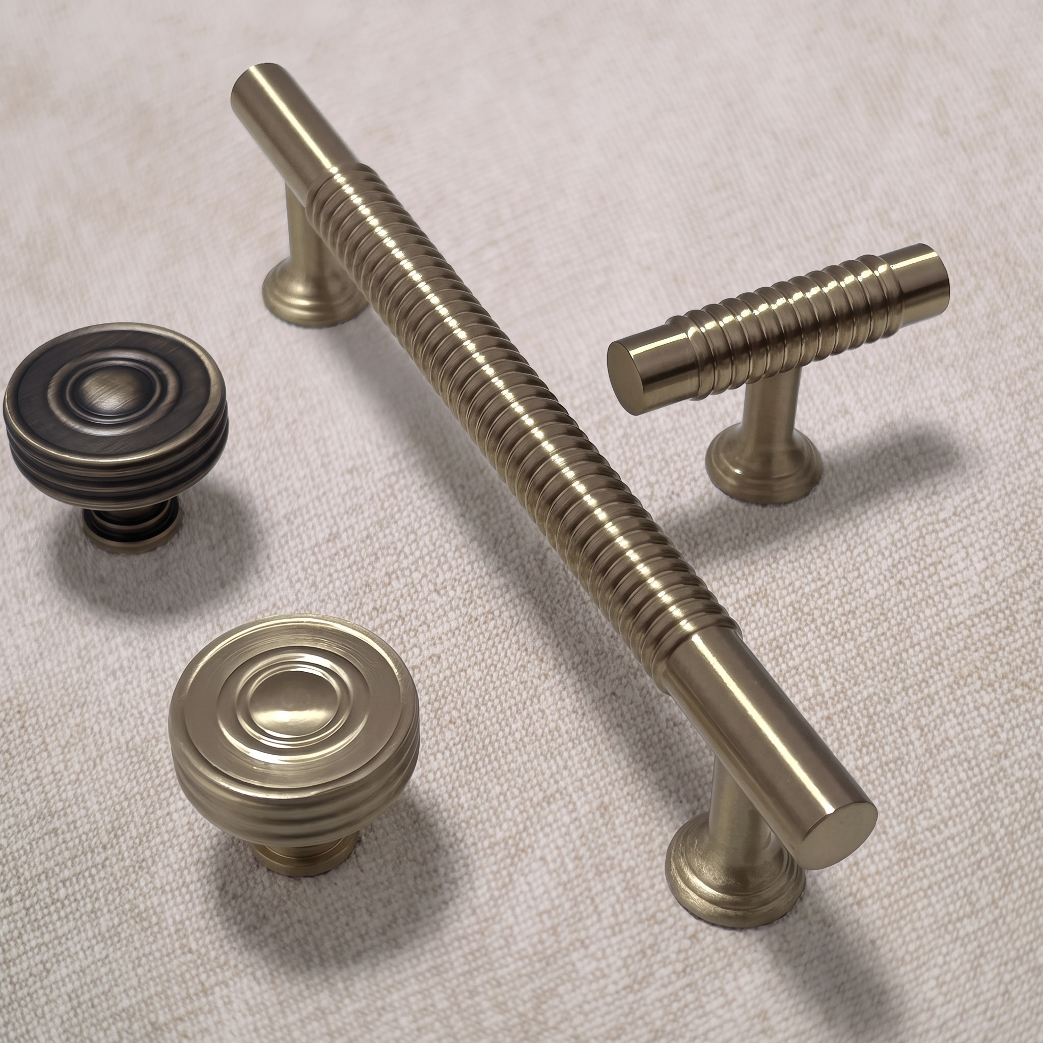 Family arrangement of two circular knobs and two spiral-textured pulls on pale linen, with ridges wrapping the bar and T-bar handles