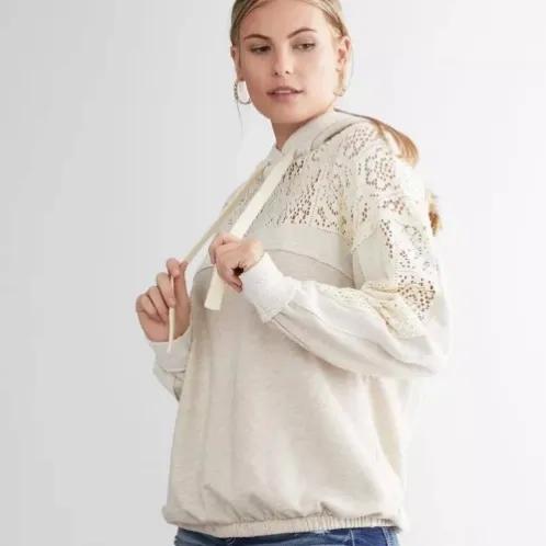 Model holding the drawstrings of a cream lace-trimmed hoodie