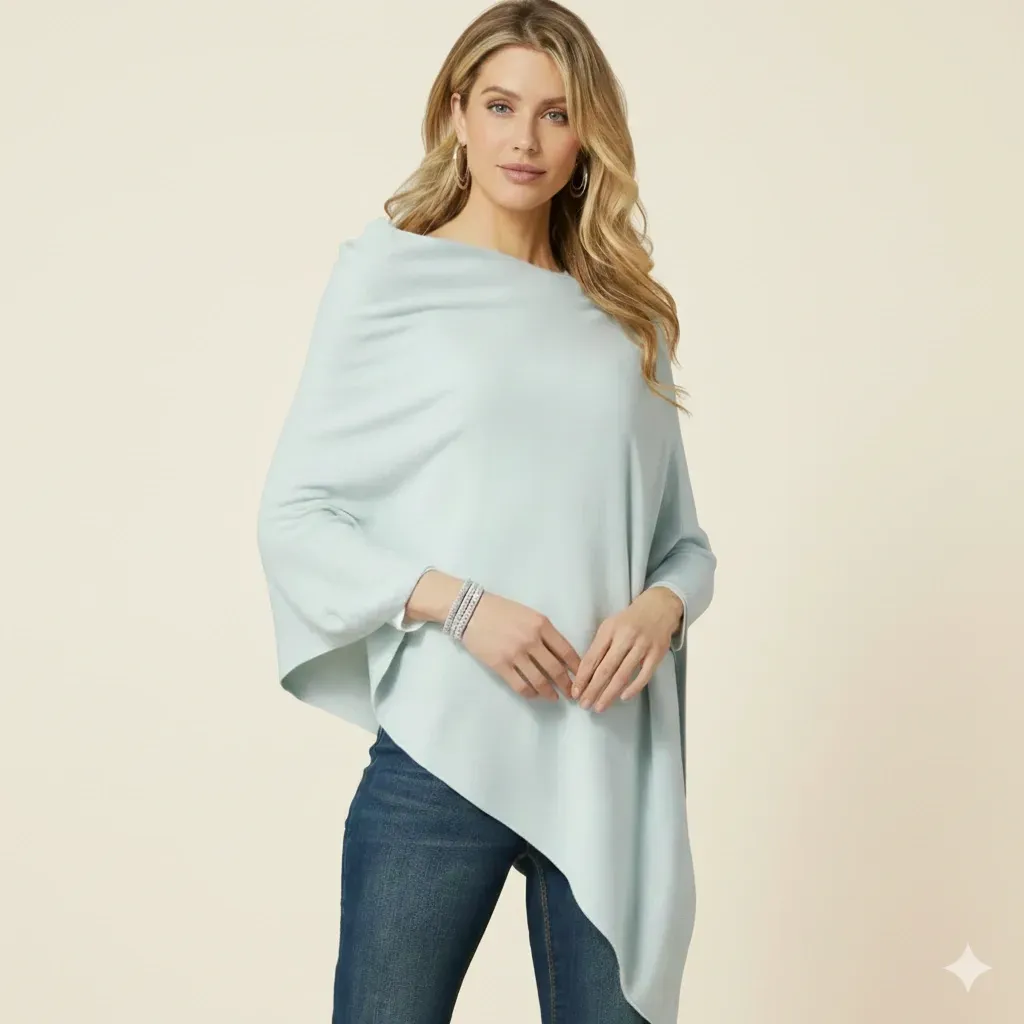 Front view of a mint green knit poncho with an asymmetric hemline, styled with blue jeans