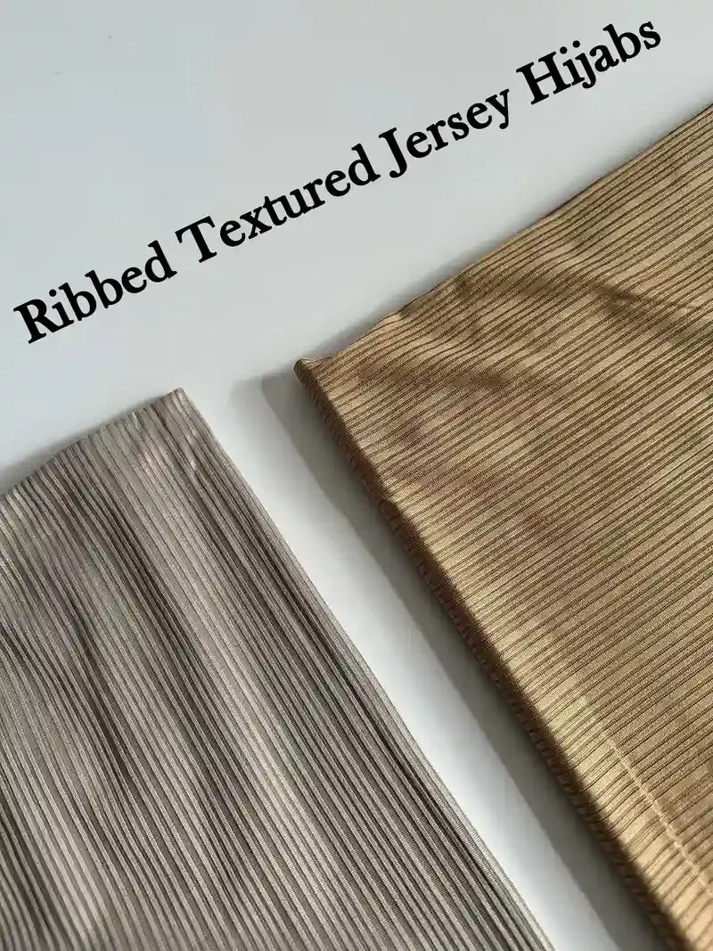 Flat lay of ribbed textured jersey hijab fabrics in grey and gold with the collection title