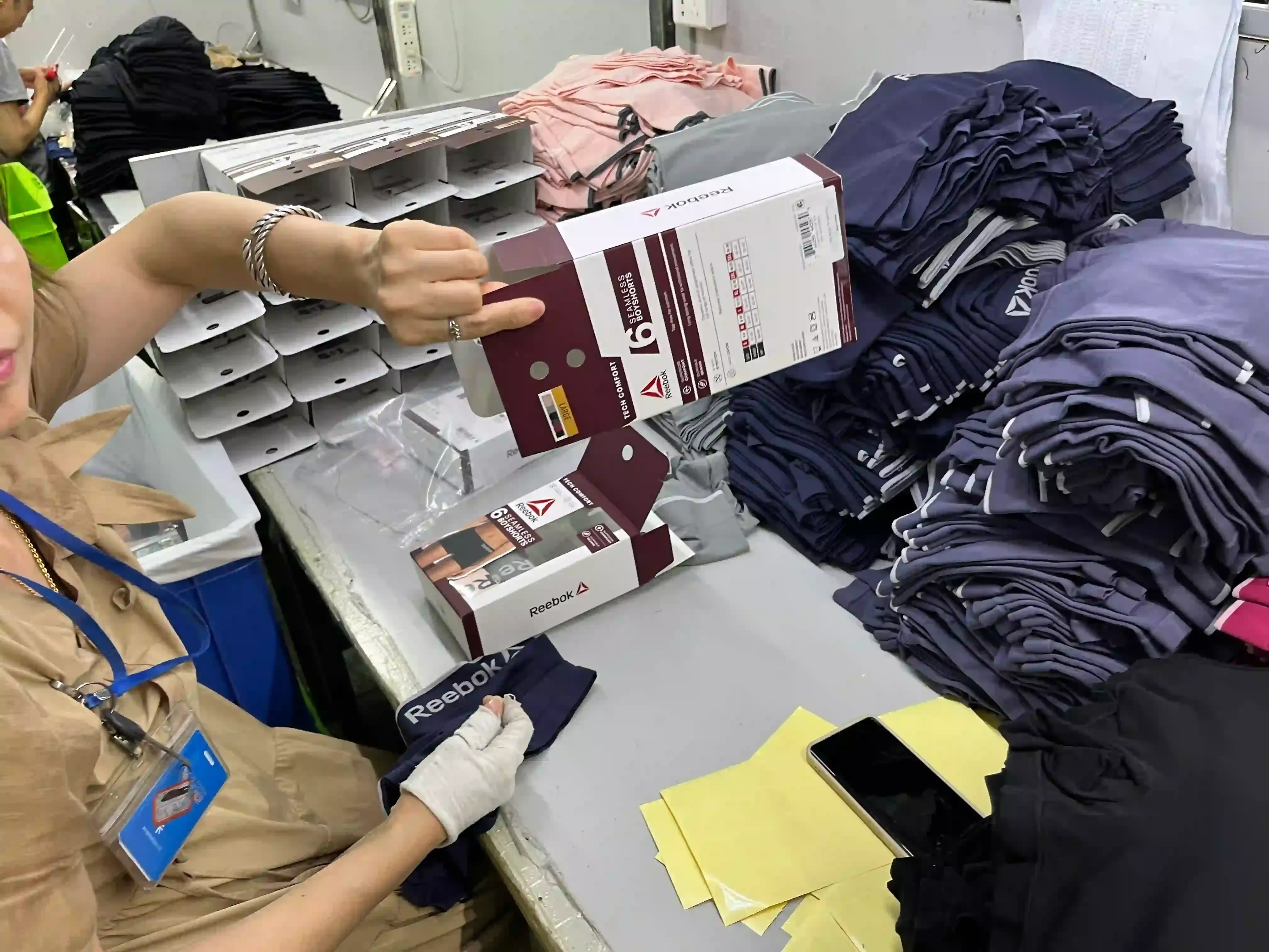 Worker packing boxed knitwear orders at the garment packing station