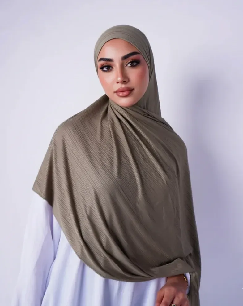 Front view of a taupe ribbed jersey hijab styled over a light blue top
