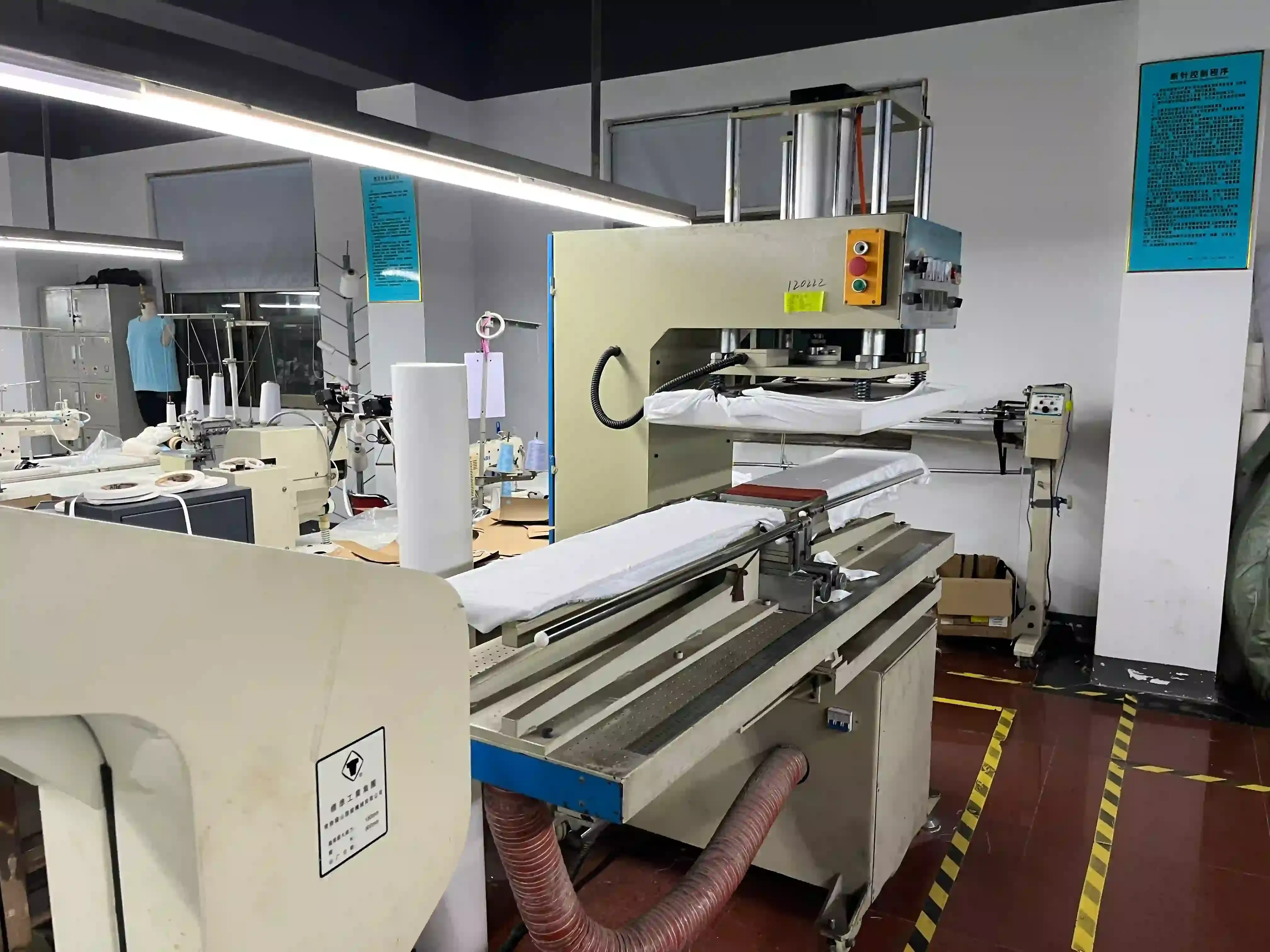 Wide view of a garment heat press machine and worktable inside the factory workshop