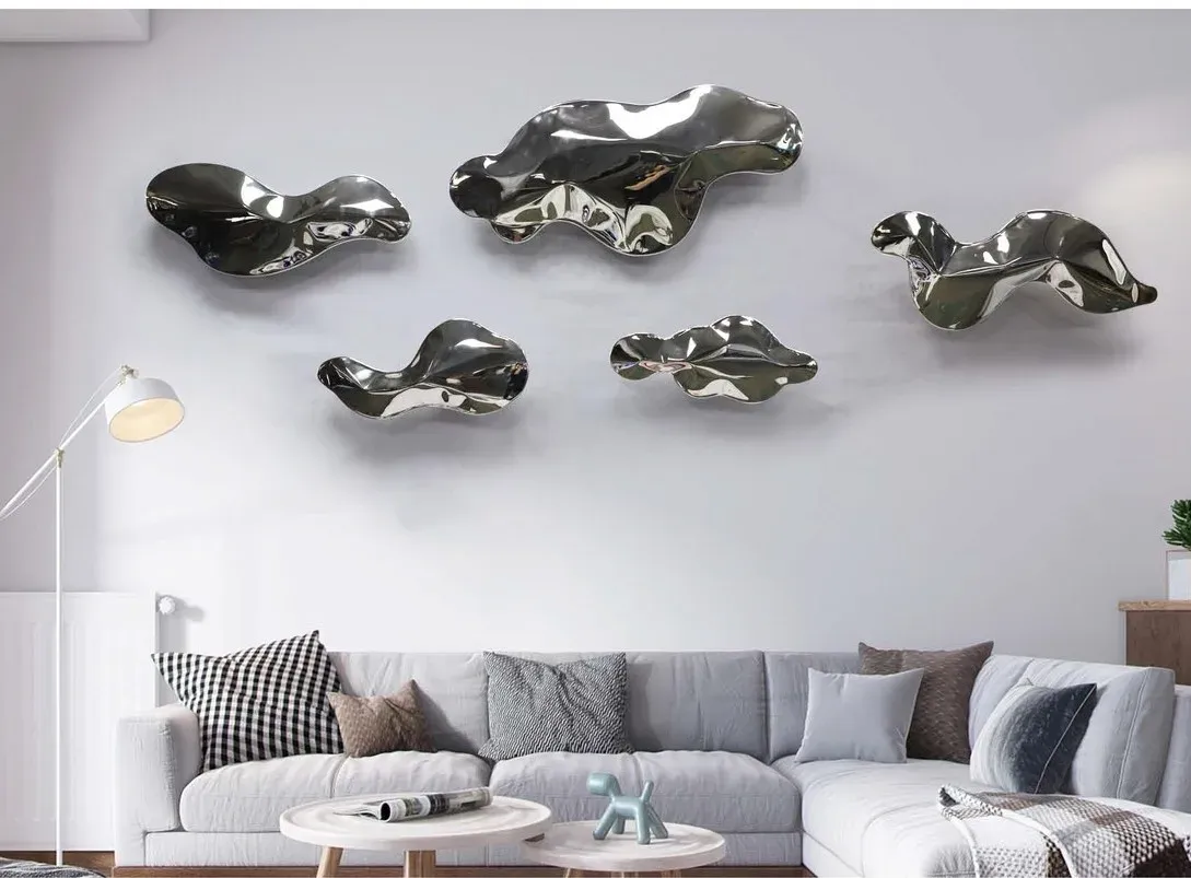 Polished silver modular wall sculpture arranged above a sofa