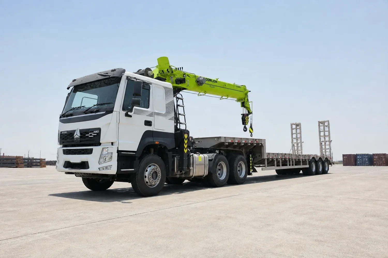 Crane lorry and lowbed trailer on a wide open concrete hardstanding under high noon heat haze, importing a crane truck into Saudi Arabia