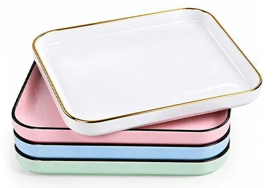 Stacked rectangular ceramic serving trays with rounded corners in white, pink, blue and green, with gold-colored rims.