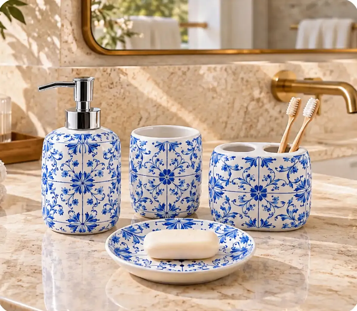 Blue-and-white floral ceramic bathroom set with a soap dispenser, tumbler, toothbrush holder and soap dish beside a sink.