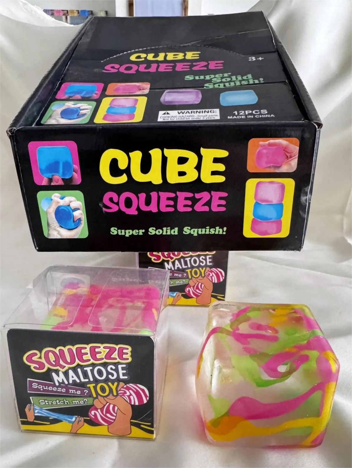 Multicolour squishy cube reference beside individual and display packaging