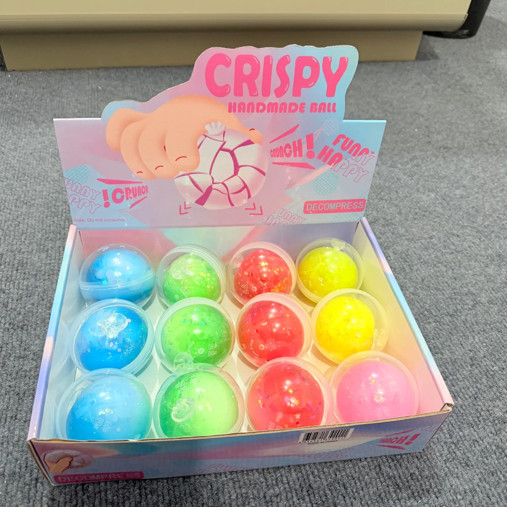 Colourful clear ball-shaped squishy toys in a Crispy display box