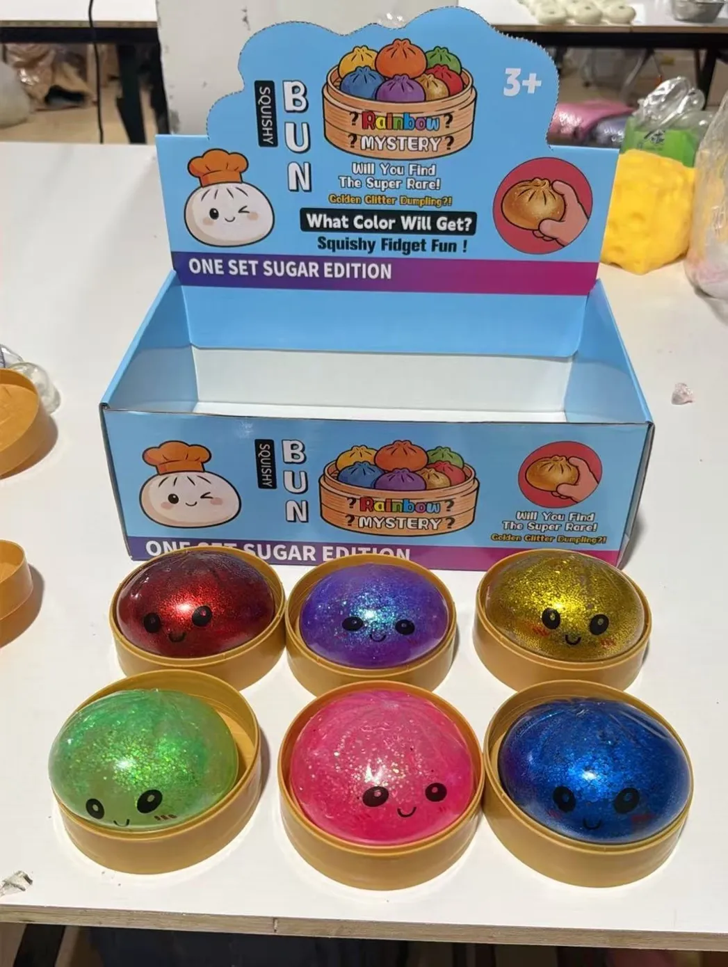 Glitter-look dumpling-shaped squishy toys in round tubs with display packaging