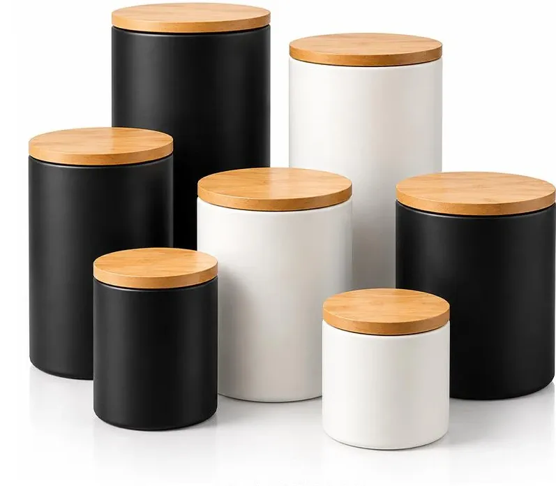 Black and white cylindrical ceramic storage jars in several heights with wood-colored lids.