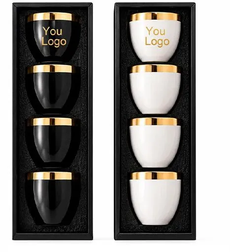 Two boxed sets of small ceramic coffee cups in black or white with gold-colored rims.Two boxed sets of small ceramic coffee cups in black or white with gold-colored rims.