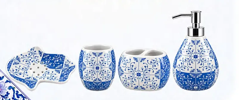 Blue-and-white ceramic bathroom set with a curved soap dispenser, rounded tumbler and toothbrush holder, and scalloped soap dish.