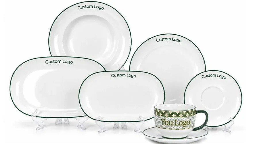 White ceramic dinnerware assortment with round and oval plates, a cup and saucer, and green Custom Logo accents.