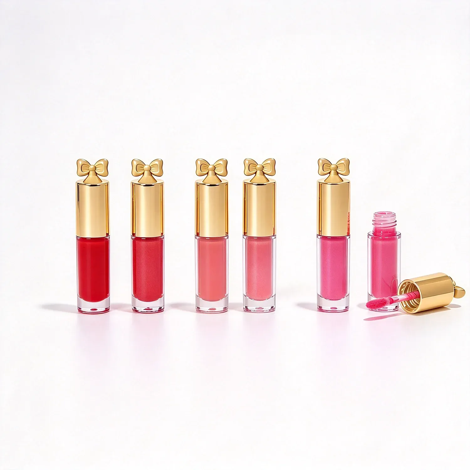 Five slim lip gloss tubes with gold caps topped with small bows