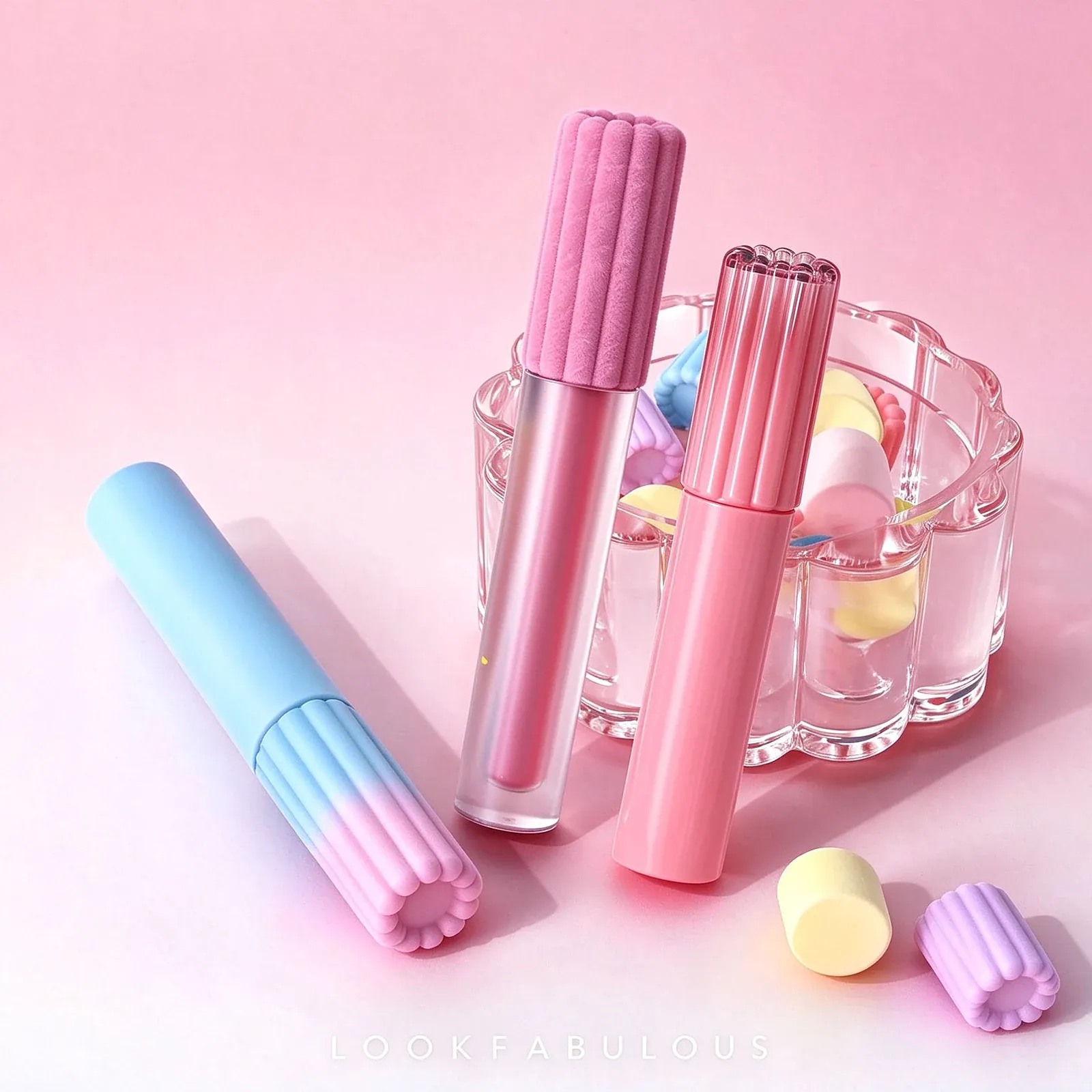 A clear pink-gloss lip glaze tube, an opaque pink tube and a blue to pink gradient tube, all with ribbed caps
