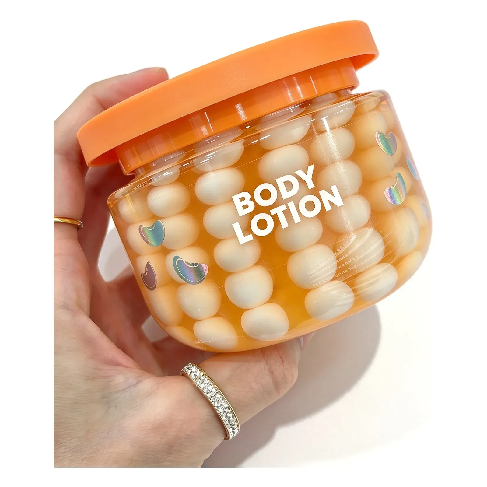Vanilla bead body lotion in a clear jar with orange lid, filled with cream lotion beads