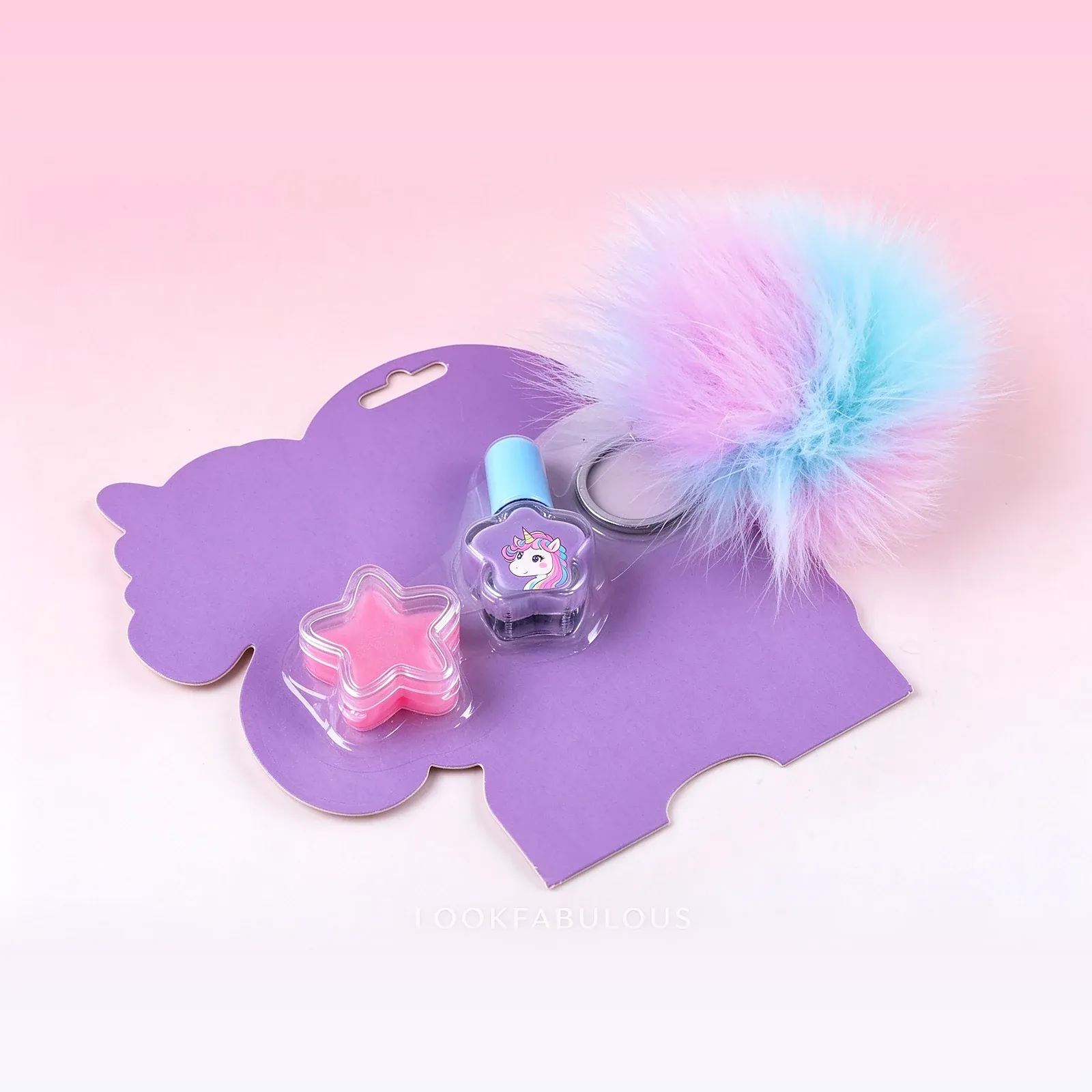 Purple unicorn card with a pink star-shaped nail polish, a purple nail polish bottle with a blue cap and a pastel pom-pom keychain
