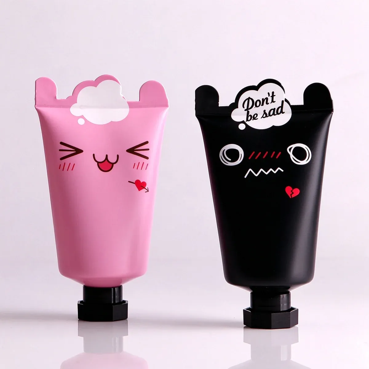 Pink smiling cat face tube and black sad face tube printed with a small cloud reading Don't be sad