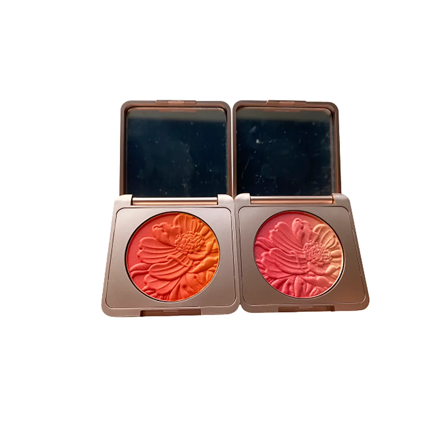 Two flower-embossed blush compacts in coral orange and rose pink with mirrors