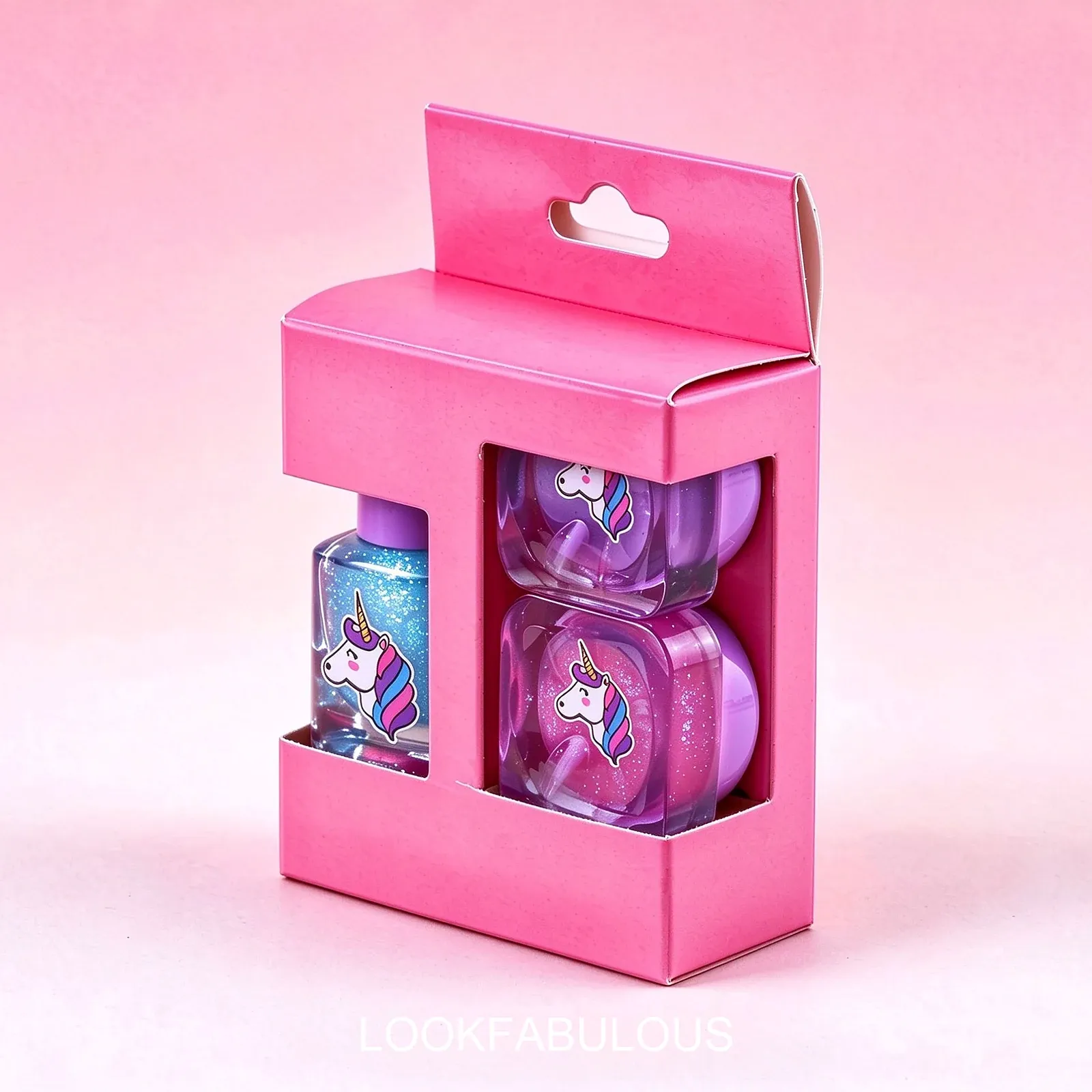 Pink carry box with a clear window holding a blue square nail polish and two rounded square purple unicorn pots