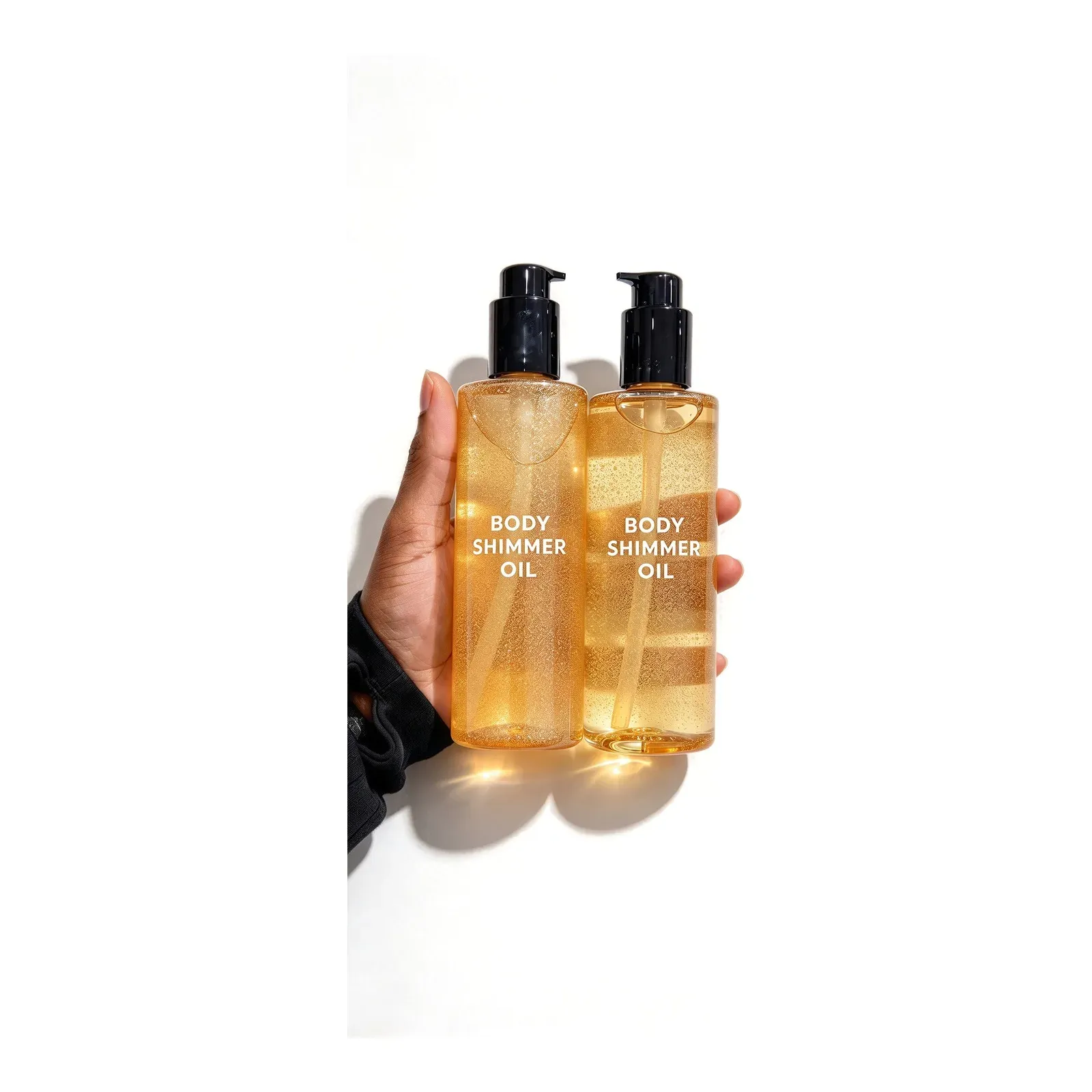 Two tall gold shimmer body oil bottles with black pump dispensers