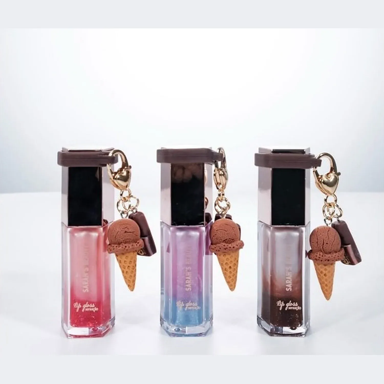 Three lip gloss tubes with ice cream cone charm caps in strawberry, orange and chocolate