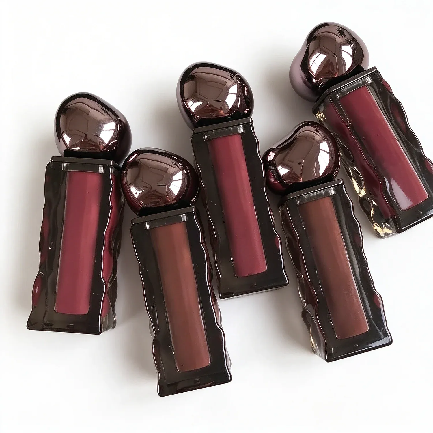 Five glossy lip gloss bottles with wavy textured bodies and rounded teardrop caps