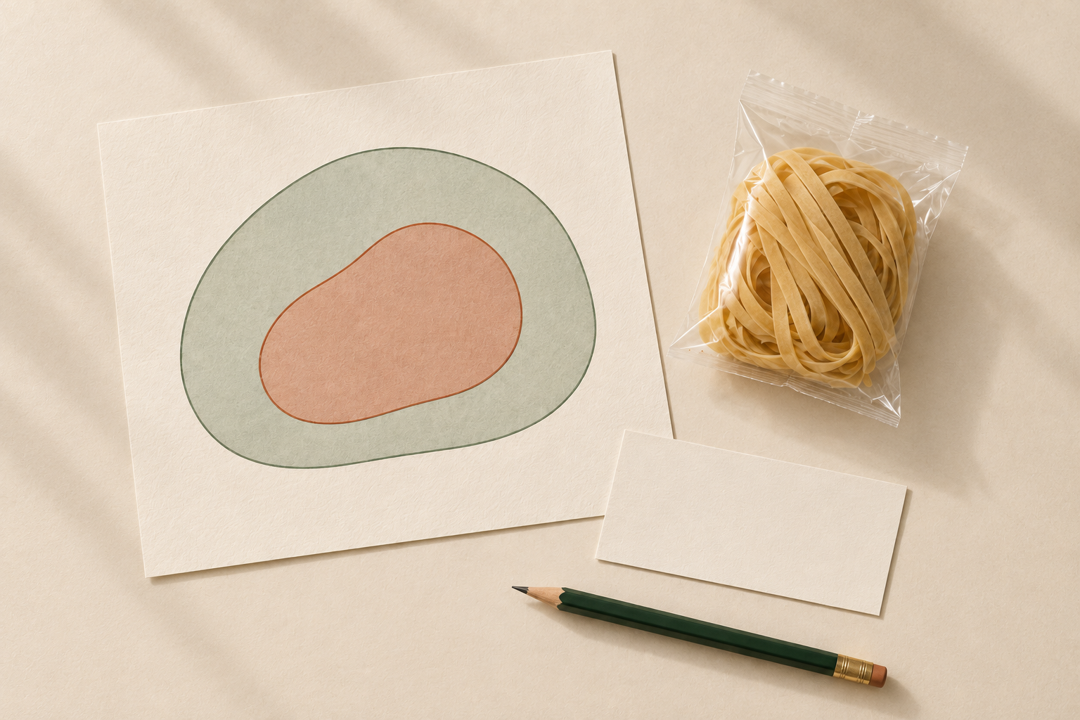 Editorial illustration of nested shapes on a paper card beside a separate wheat-noodle sample.