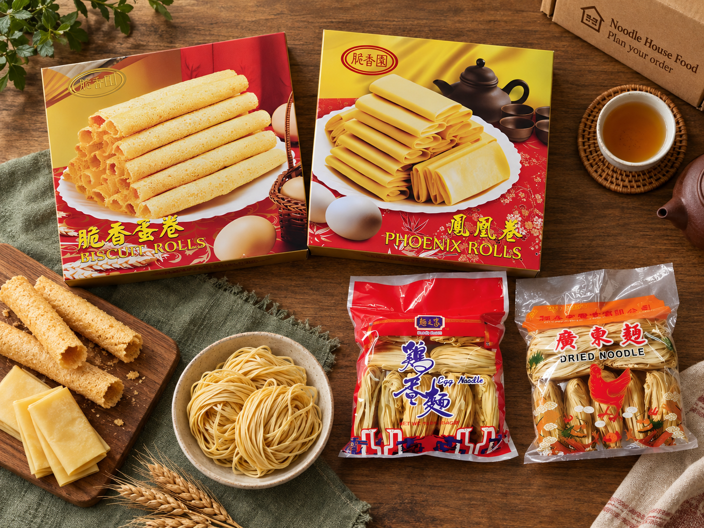 Square egg roll and phoenix roll boxes with smaller egg noodle and dried noodle bags in a tabletop flat lay