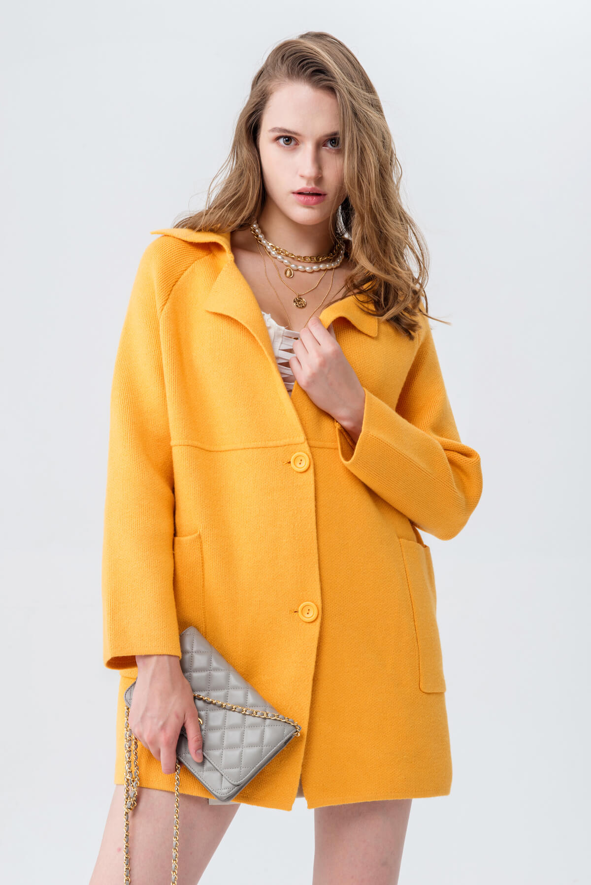 Marigold knit coat with visible shoulder seams, worn open while walking.