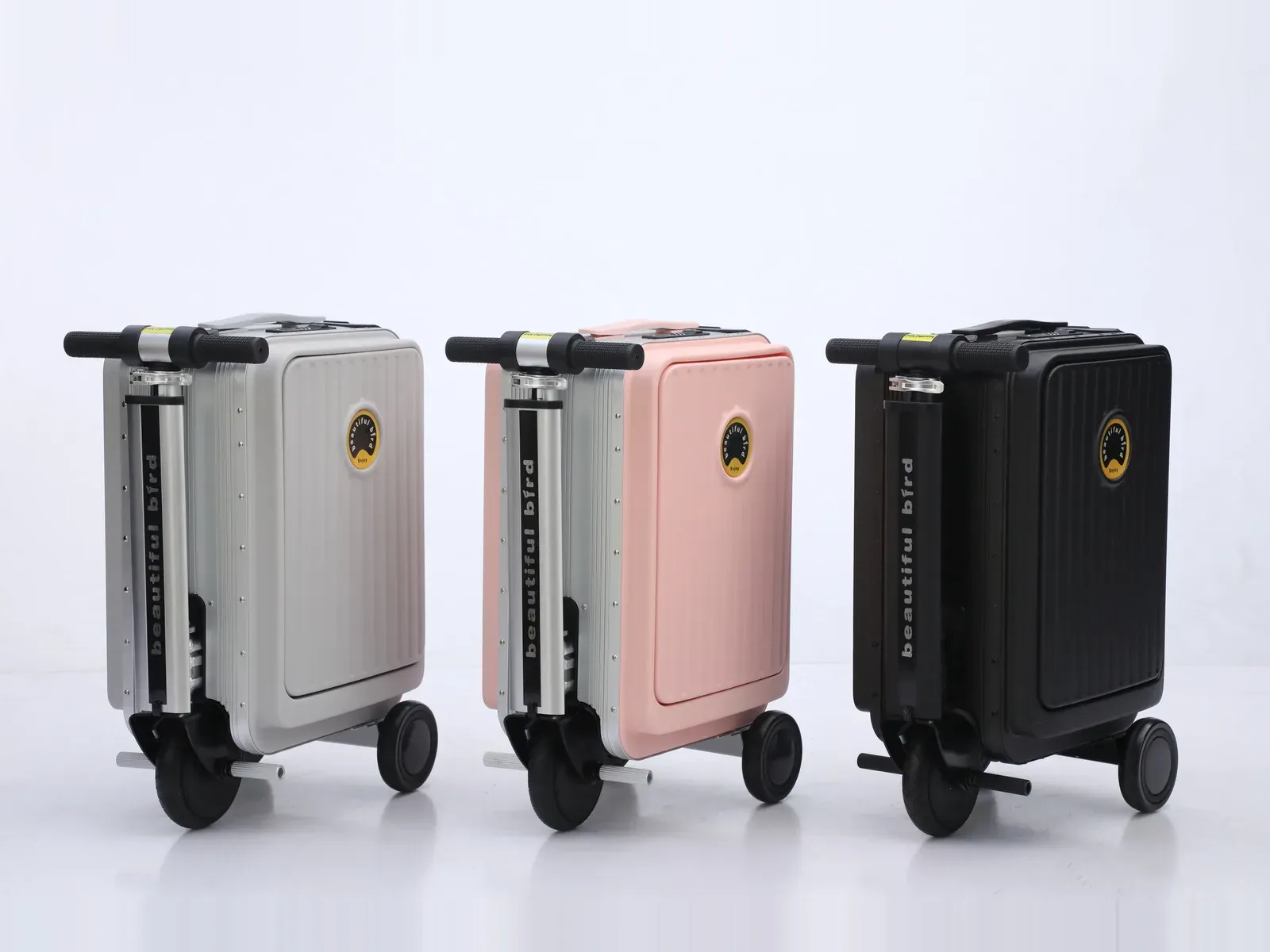 Three beautiful bird 188 ride-on electric suitcases in light grey, pink and black, each carrying the beautiful bird brand name on the telescopic handle