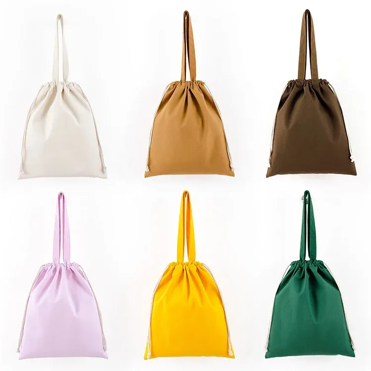 Six canvas drawstring totes in natural, mustard, brown, pink, yellow and green shown with drawstrings cinched closed