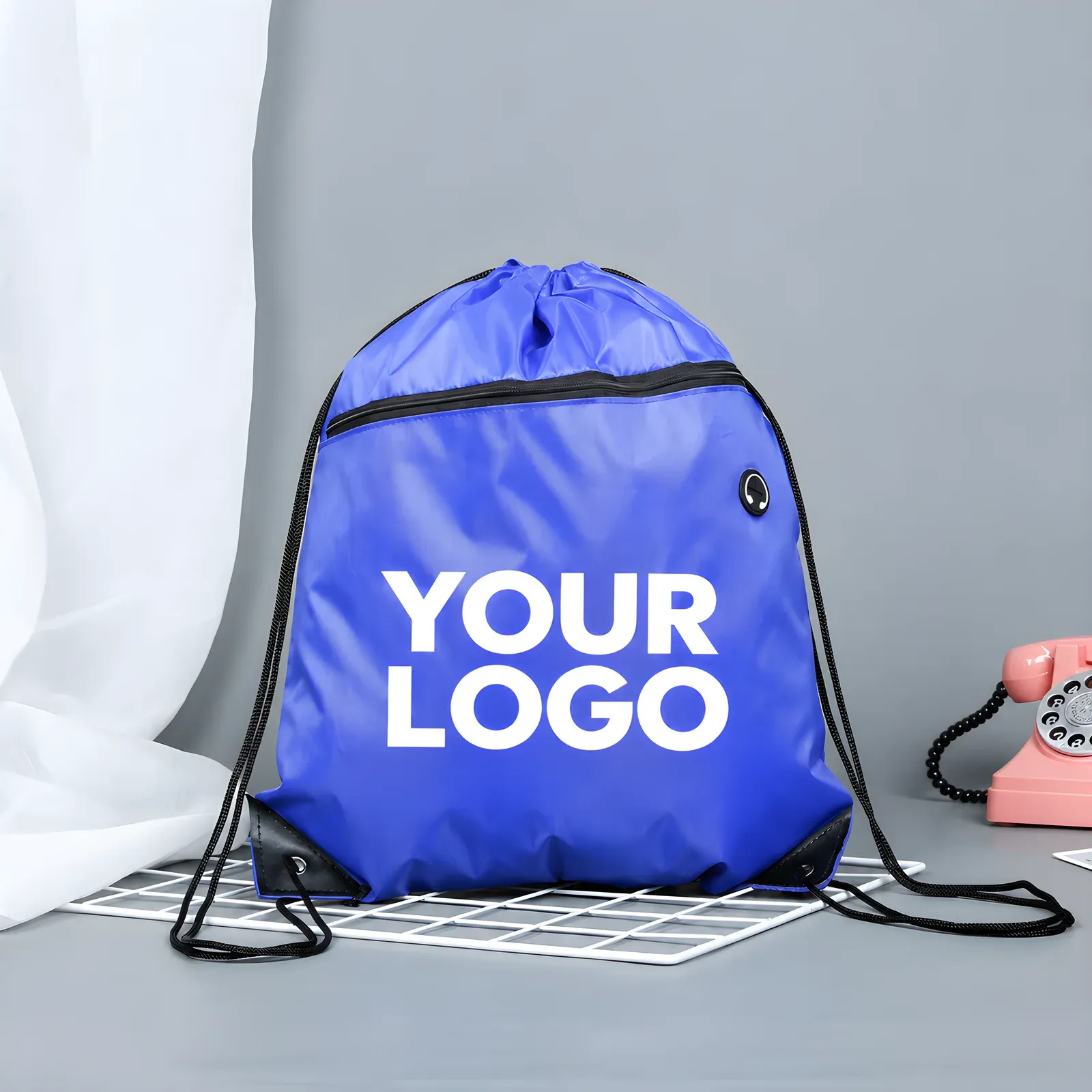 Blue heavy-duty 3000D drawstring backpack with front zip pocket and white YOUR LOGO print, on a grey studio background