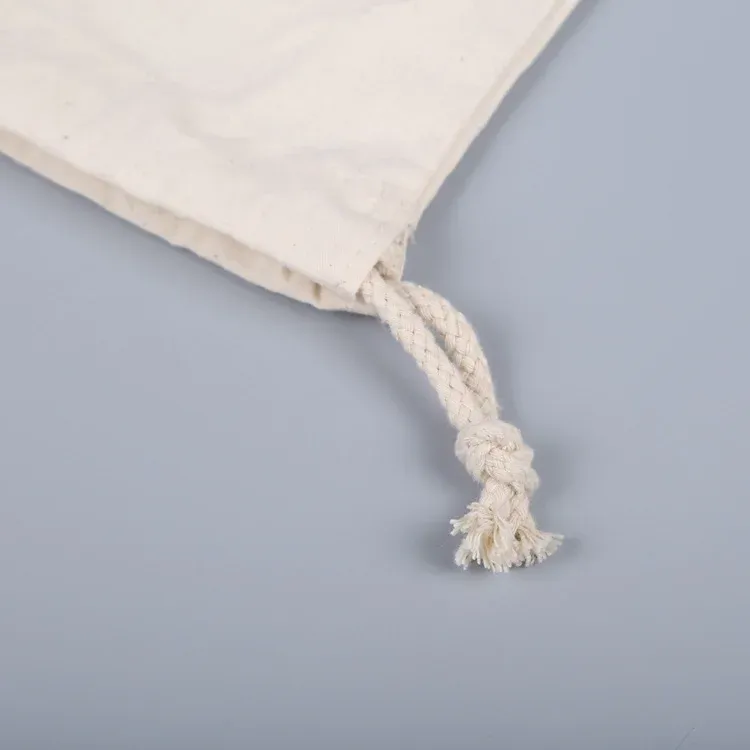 Macro close-up of the knotted cotton drawstring end on a natural canvas pouch