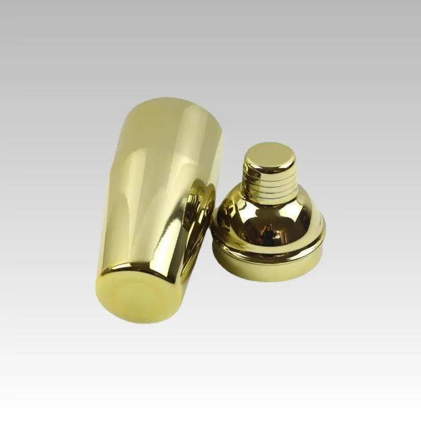 Gold cocktail shaker body and domed top with cap placed side by side on a white background