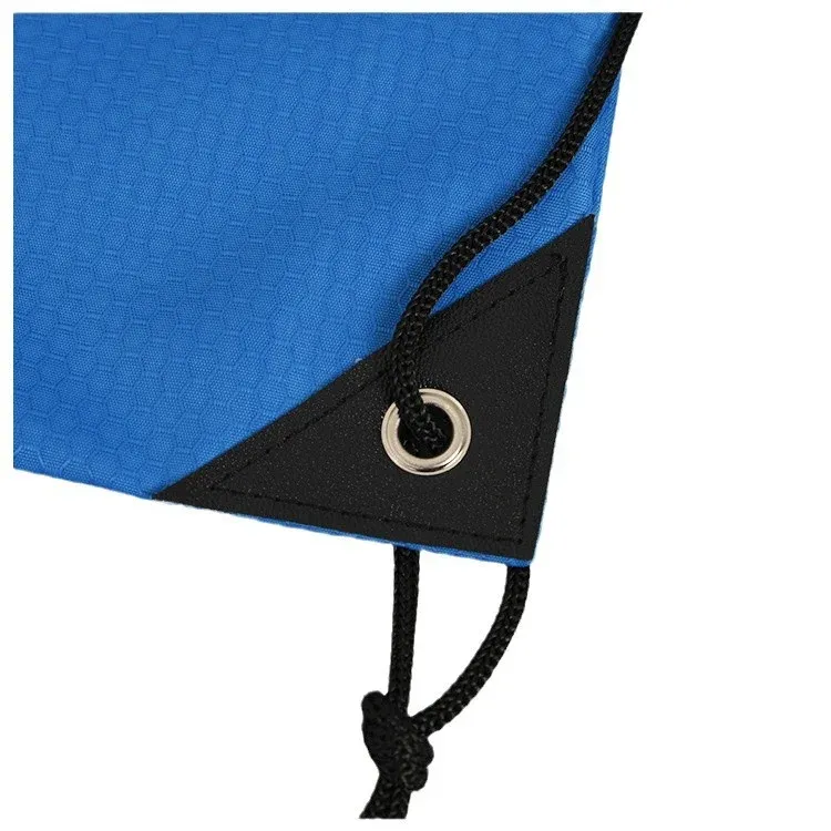 Close-up of the black reinforced corner patch with metal eyelet and knotted black drawcord on a royal blue drawstring backpack