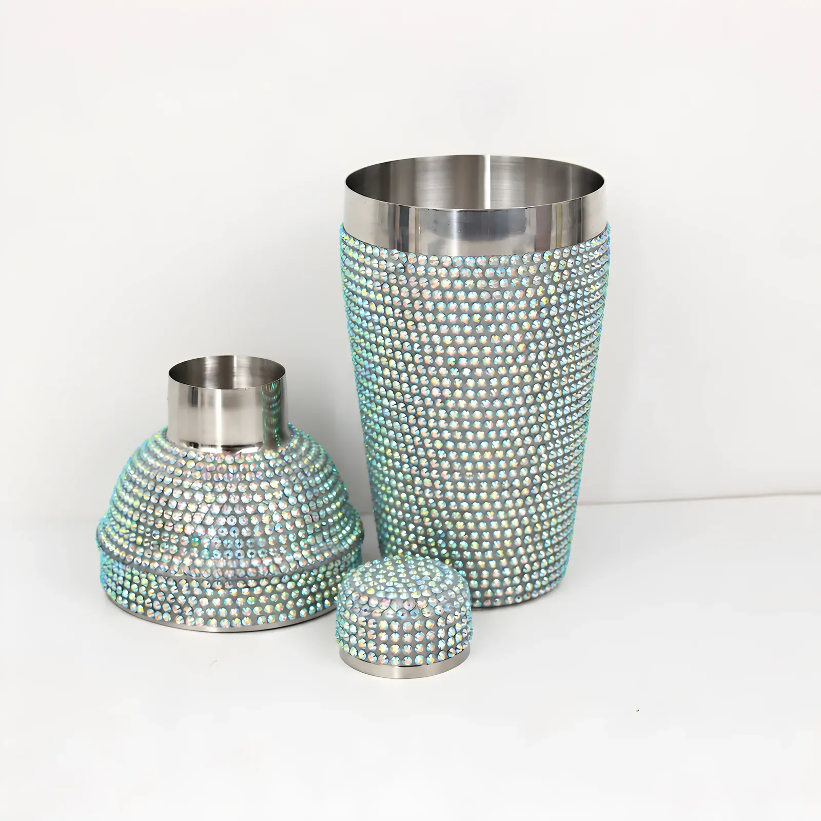 Rhinestone-covered cocktail shaker taken apart showing its stainless steel interior, strainer top and cap
