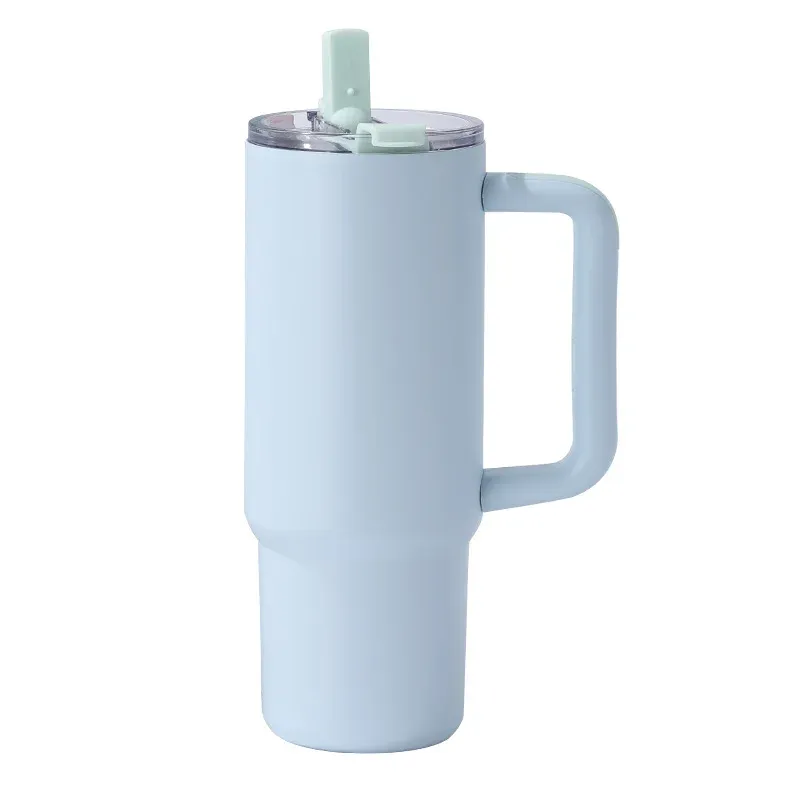Light blue insulated tumbler with molded side handle, clear lid with mint green straw tab, three-quarter view on white background