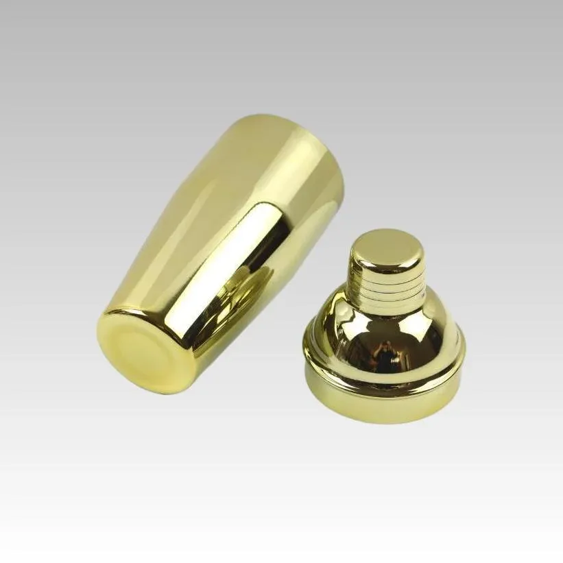 Gold cocktail shaker with its domed top removed, body and top shown side by side