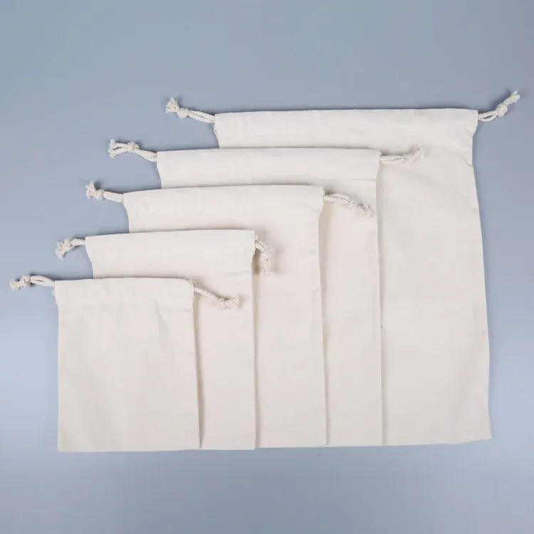 Five natural canvas drawstring pouches in graduated sizes arranged small to large on a grey background