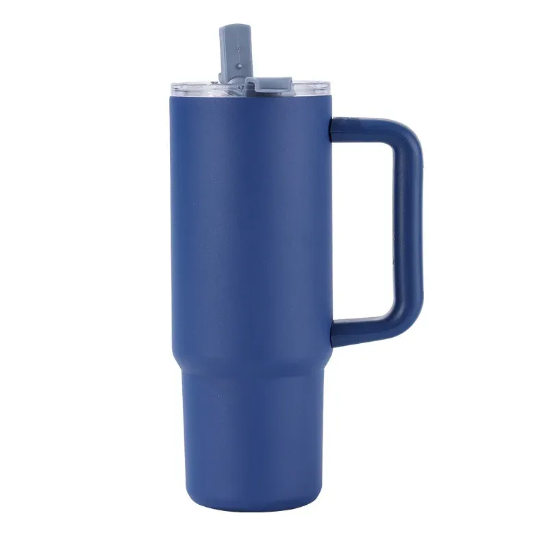 Navy blue insulated tumbler with molded side handle, clear lid with navy straw, three-quarter view on white background