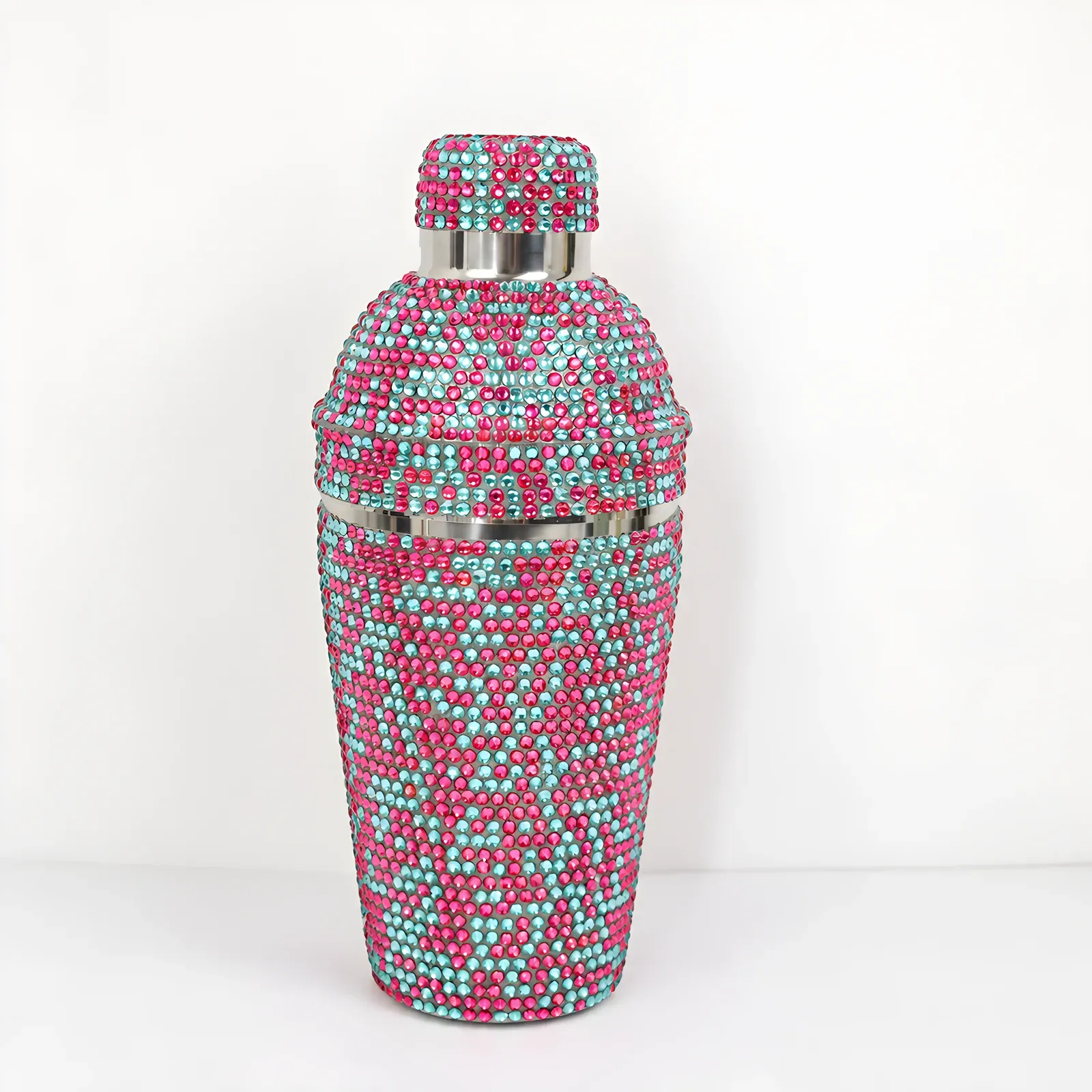 Cocktail shaker fully covered in pink and teal rhinestones on a white background