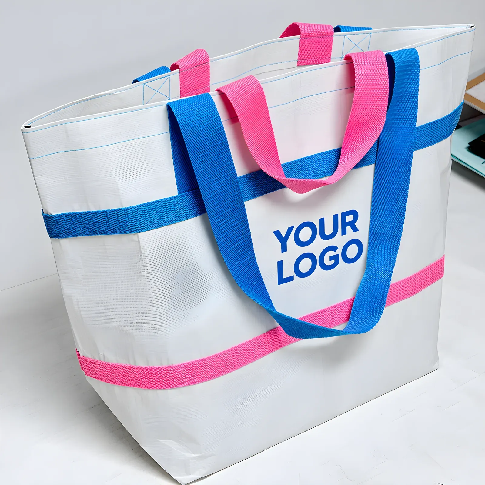 Angled view of the blue and pink contrast trim RPET tote on a desk