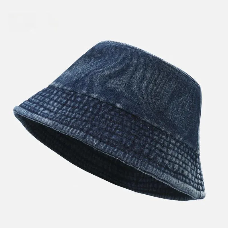 Dark blue washed cotton denim bucket hat with faded texture and quilted stitched brim, angled view